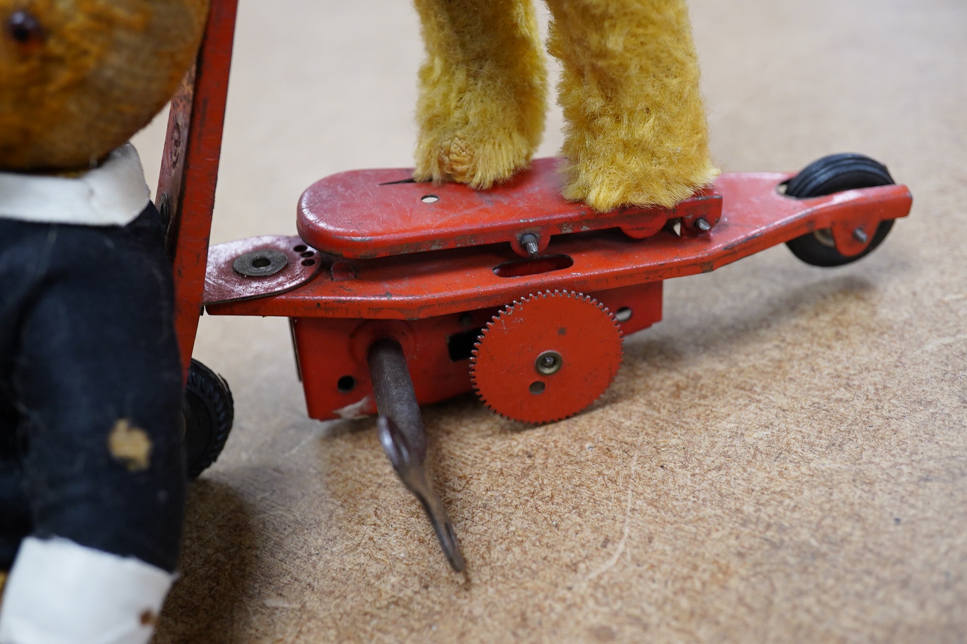 A mechanical bear on a bike in good working condition, a red Schuco bear, faded condition, c.1920, 13cm, a tumbling Schuco bear, working, 10cm, c.1920, a green Schuco bear missing one ear, c.1920, 7cm. high, together wit